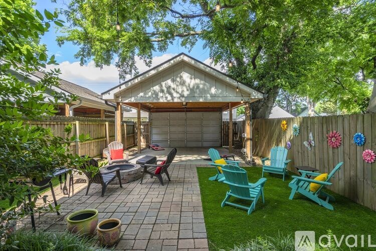 A backyard with a patio, chairs, and a fence.