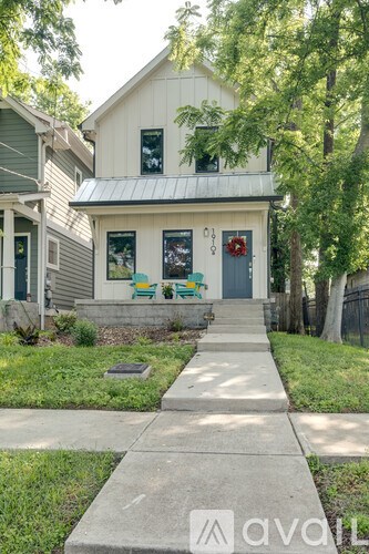 A white house with a green door and a red wreath on the door.
