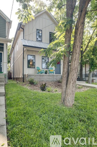 A house with a green lawn and a tree in front.