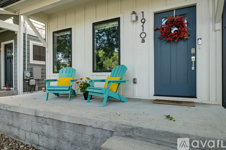 Two chairs and a table are on the porch of a house.