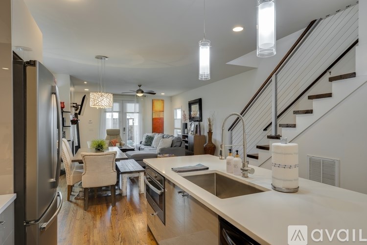 A modern kitchen with a refrigerator, sink, and stairs in the background.