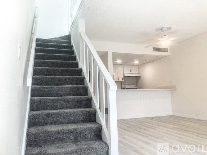 A staircase with a carpeted runner and white railings leads up to a kitchen area.