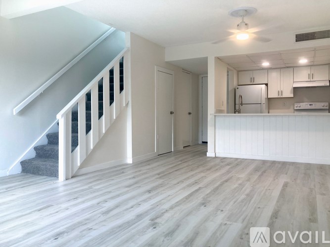 A spacious room with a staircase and a kitchen area.