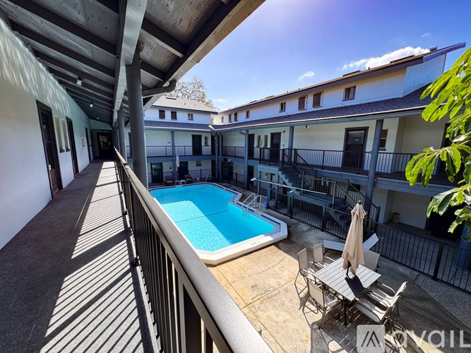 A sunny day at the poolside with a chair and umbrella.