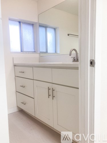 A bathroom with a sink, mirror, and cabinets.