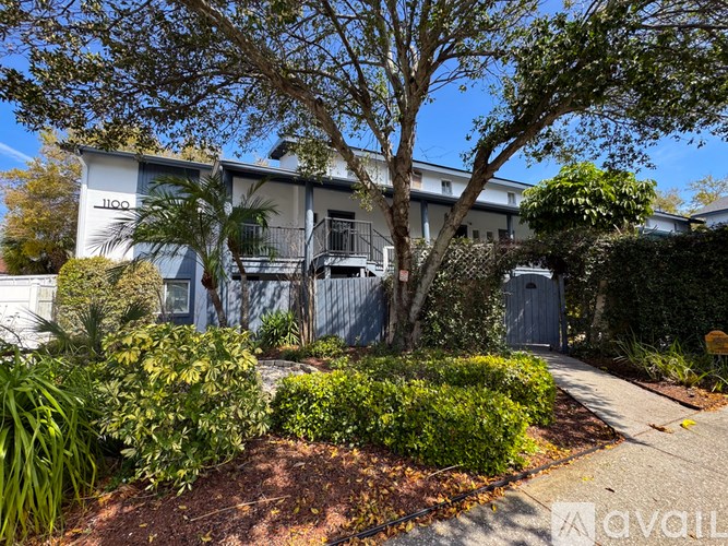 A tree in front of a building with the number 1100 on it.