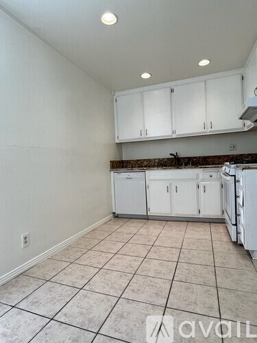 A kitchen with white cabinets and a tiled floor.