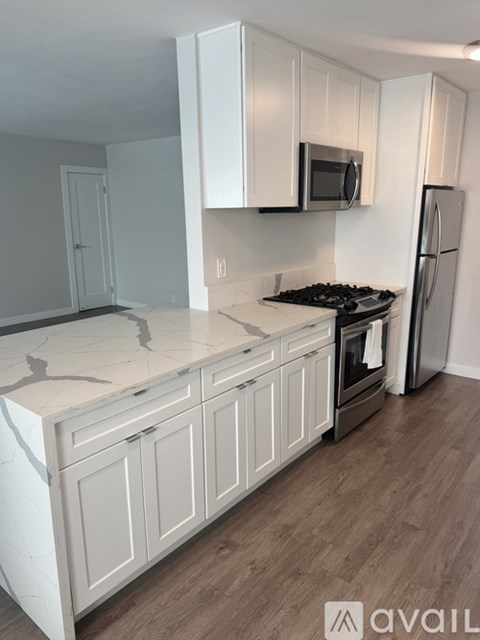 A kitchen with white cabinets and a marble countertop.