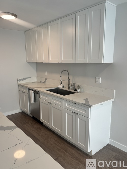 A kitchen with white cabinets and a marble countertop.
