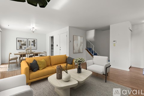A living room with a yellow couch and a white chair.
