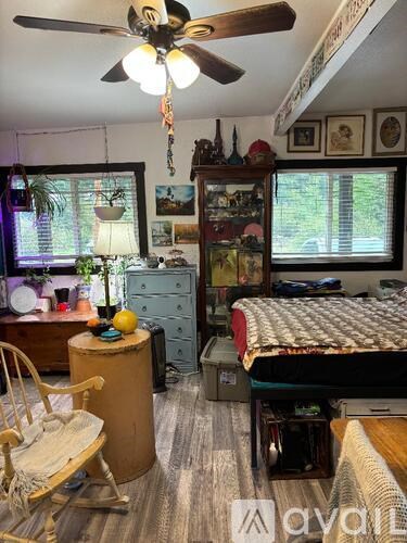 A room with a bed, a chair, a dresser, and a ceiling fan.