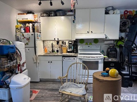 A kitchen with white cabinets and a lot of clutter.