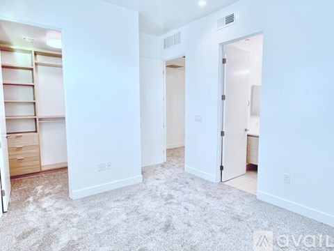 A white room with a carpeted floor and a doorway leading to another room.