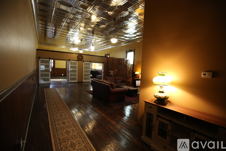A living room with a brown leather couch and a wooden floor.