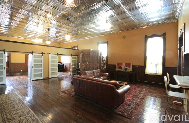A living room with a brown leather couch and a wooden floor.