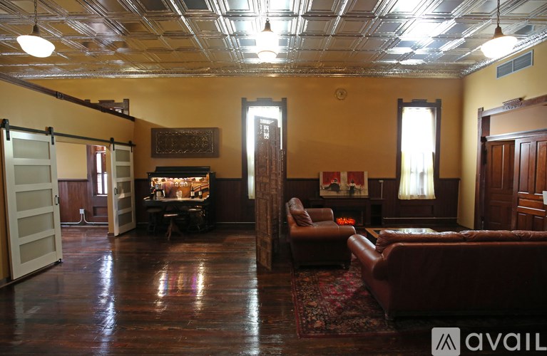 A living room with a brown leather couch and a wooden floor.