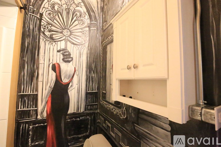 A mural of a woman in a red dress is painted on a bathroom wall.
