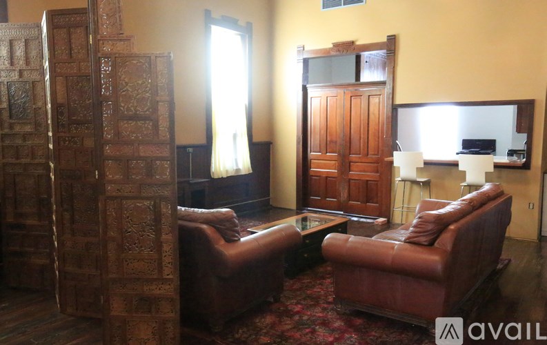 A living room with a brown leather couch and a wooden cabinet.