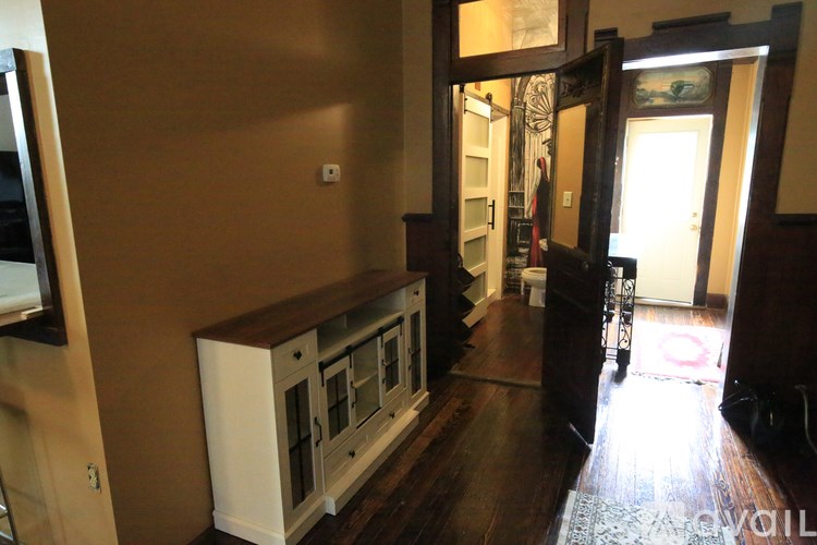 A room with a white cabinet and a mirror on the wall.