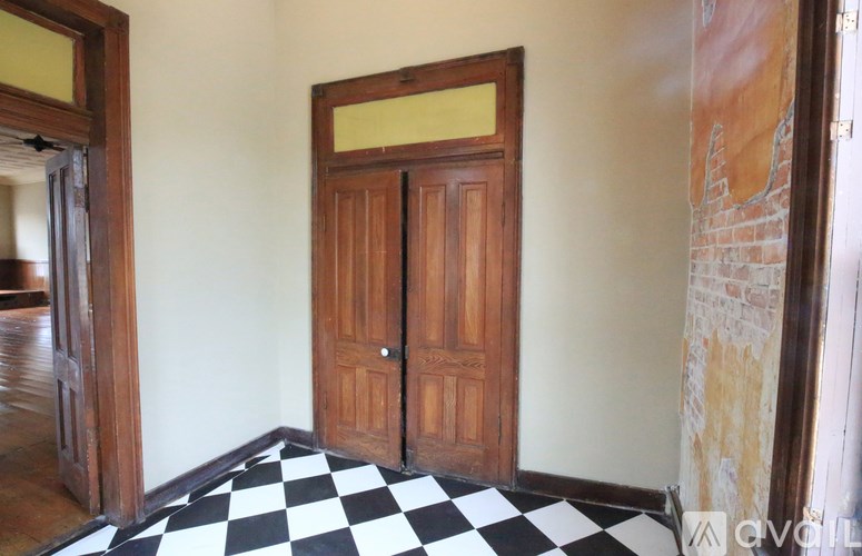 A room with a checkered floor and a wooden door.