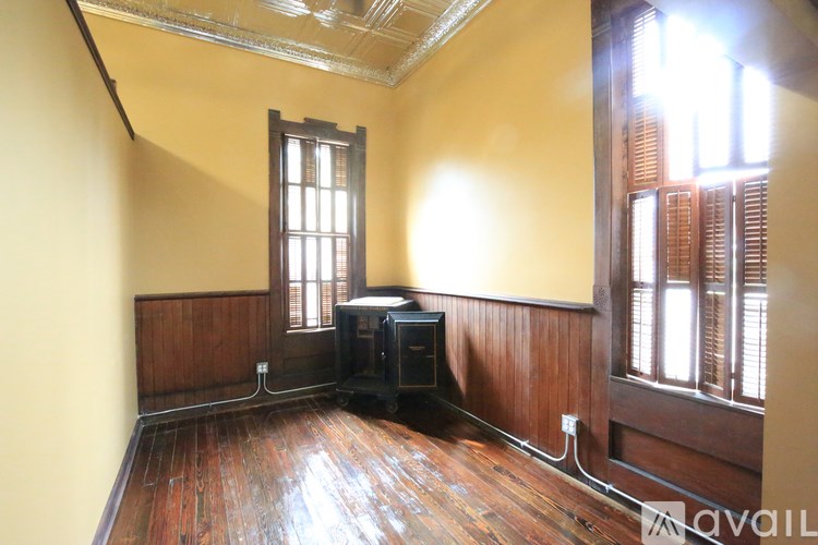 A room with wooden floors and a window with blinds.