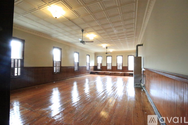 A large empty room with wooden floors and windows on the side.