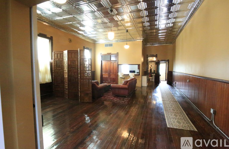 A living room with hardwood floors and a variety of furniture.