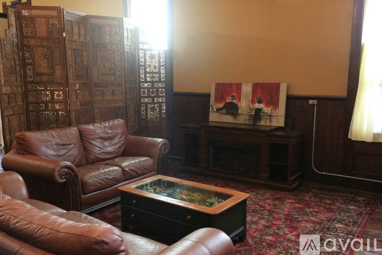 A living room with brown leather furniture and a painting on the wall.