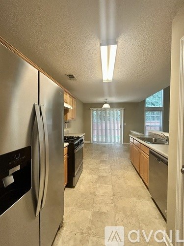 A kitchen with a stainless steel refrigerator and wooden cabinets.