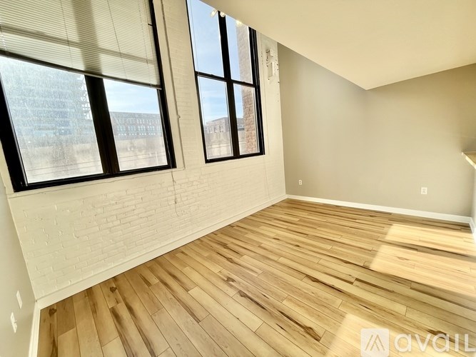 A room with wooden flooring and large windows.