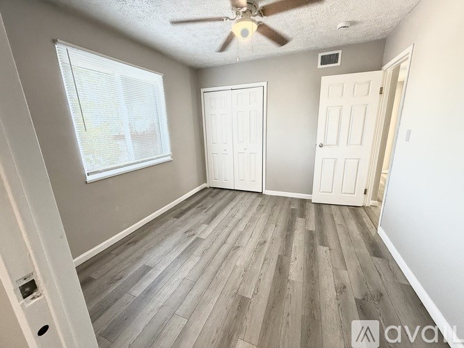 A room with a ceiling fan and wooden flooring.