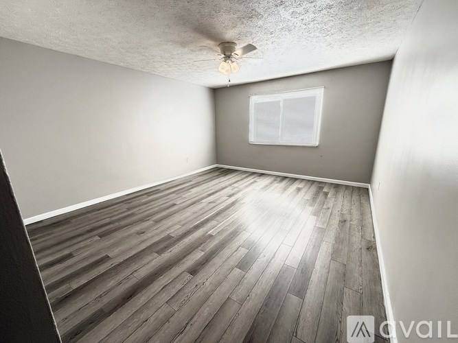 A room with wooden flooring and a ceiling fan.