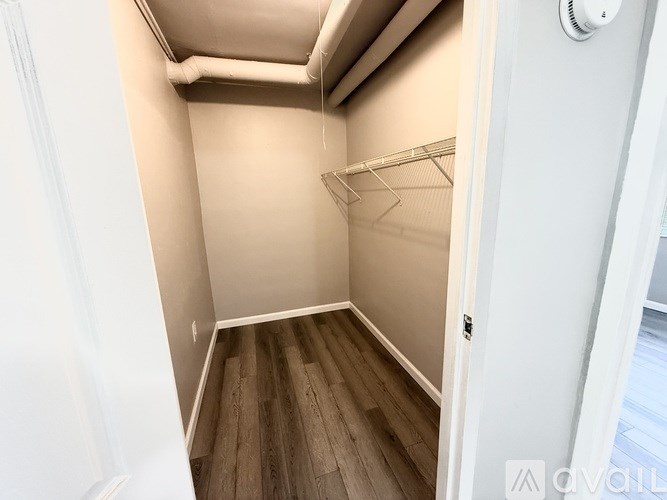 A small, empty closet with a wooden floor and white walls.