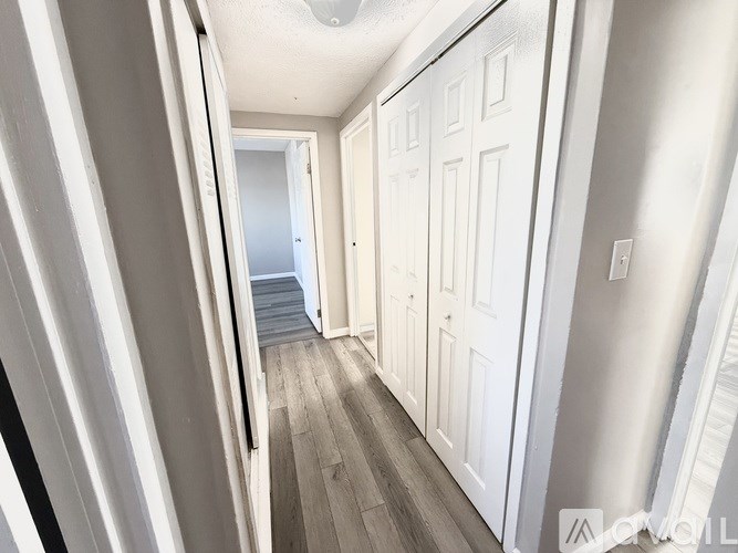 A hallway with white doors and a wooden floor.