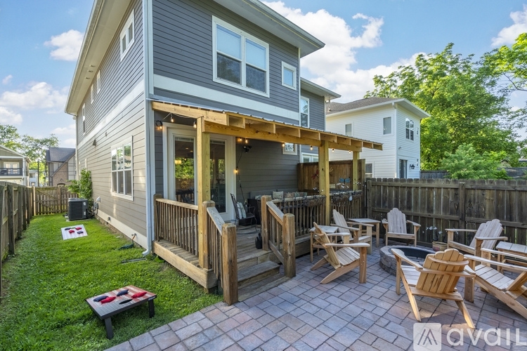 A house with a grey exterior and a wooden deck with chairs.