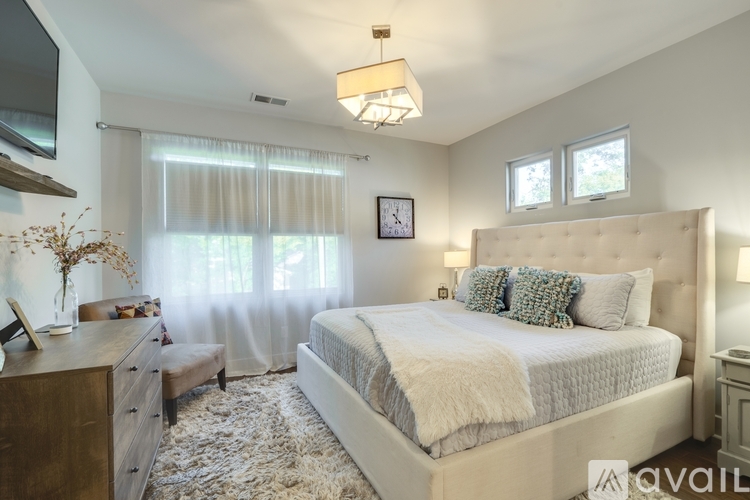 A bedroom with a large bed, a dresser, and a window with curtains.