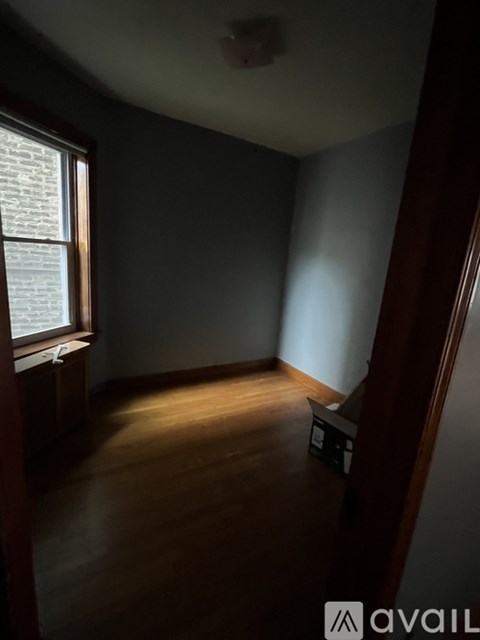 A room with a window and wooden floors.