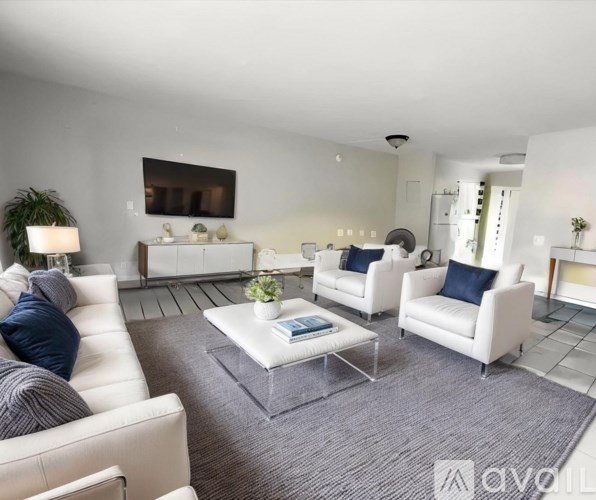 A living room with white furniture and a grey rug.