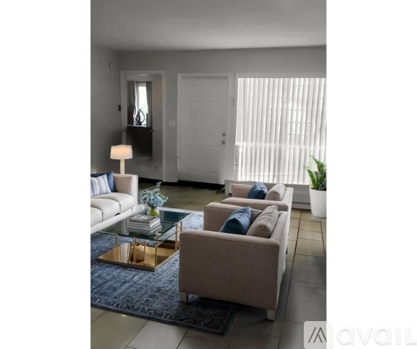A living room with a white sofa, a glass coffee table, and a blue rug.