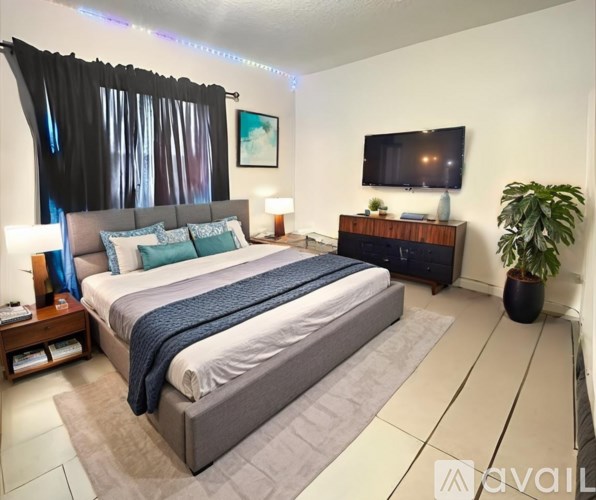 A bedroom with a large bed and a flat screen TV mounted on the wall.