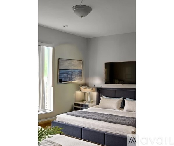 A bedroom with a bed, a painting, a lamp, and a mirror.