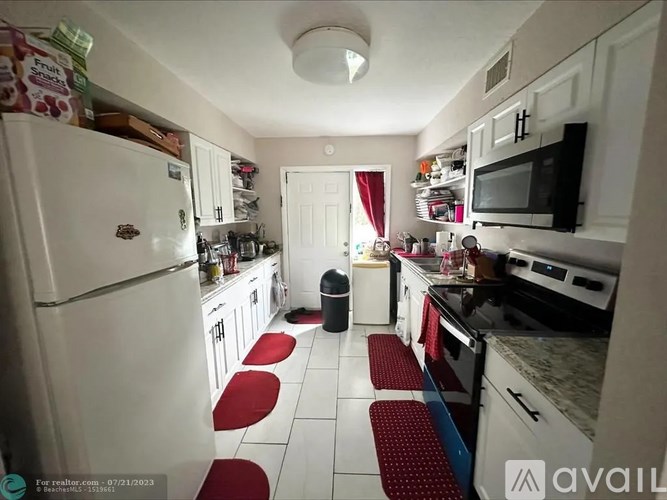 A kitchen with white appliances and red stools.