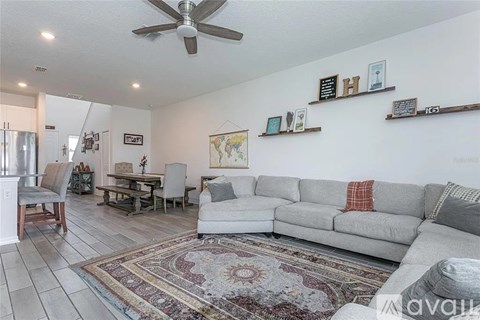 A living room with a grey couch and a rug on the floor.