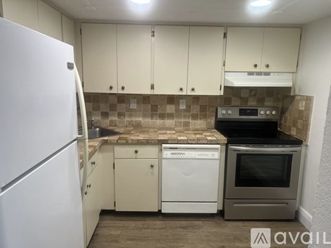 A kitchen with a white fridge, white dishwasher and a black oven.