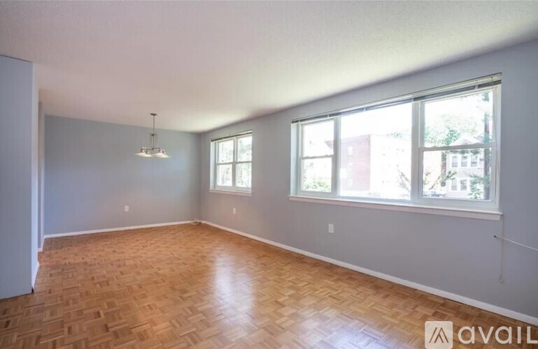 A room with wooden flooring and two windows.