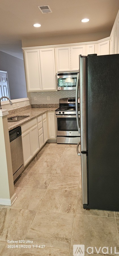 A kitchen with a black refrigerator and beige cabinets.