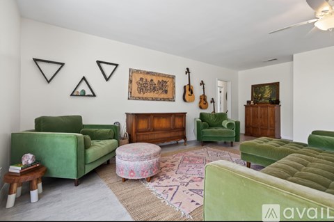 A living room with green couches and a rug.