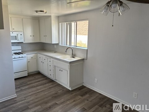 A kitchen with white cabinets and a wooden floor.
