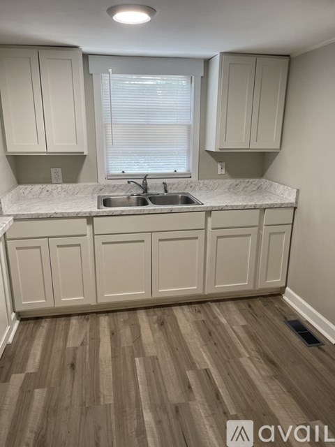 A kitchen with white cabinets and a marble countertop.