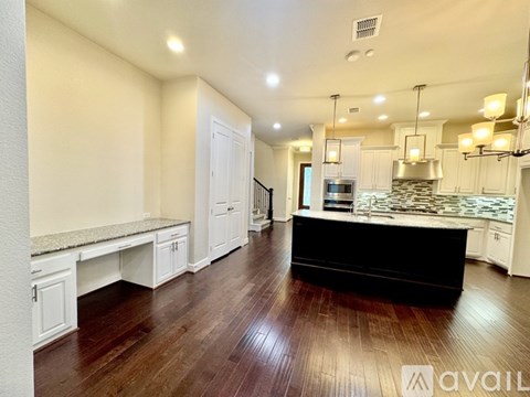 A kitchen with white cabinets and a black island.